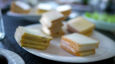 Slices of cheese on plate, traditional swiss raclette pieces