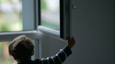 Child closing window. Toddler closes window
