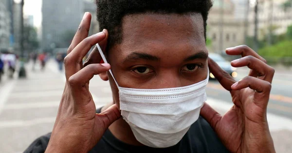 African male removing covid-19 face mask in downtown city
