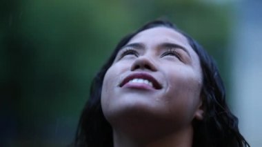 Happy woman looking up to sky while raining day
