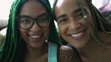 Portrait of two happy hispanic black latina young women smiling at camera