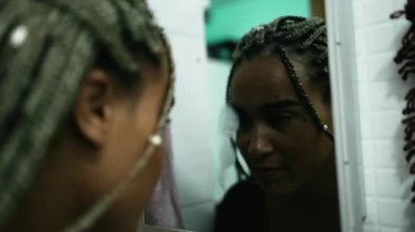 Depressed woman leaning head on bathroom mirror. One black latina girl suffering from mental illness