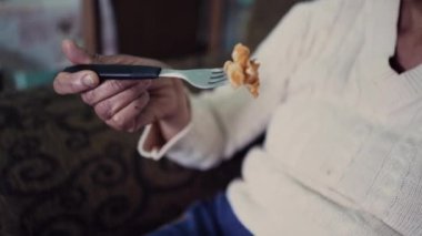 Kanepede tek başına makarna yiyen son sınıf öğrencisi bir kadın. Yalnız, yaşlı bir insan tek başına yemek yer.