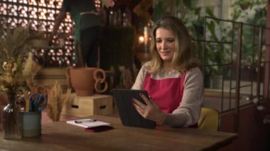 Mutlu kadın çiçekçi işletmecisi yönetici yönetici yönetici yönetici masasında oturmuş online siparişler alıyor.