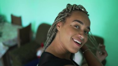 One young black woman playing with braided hair. An African American girl showing her dreadlocks box braid hairstyle