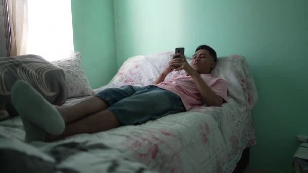 Young Hispanic Man Looking Cellphone Device Bedroom Lying Bed — Stok video