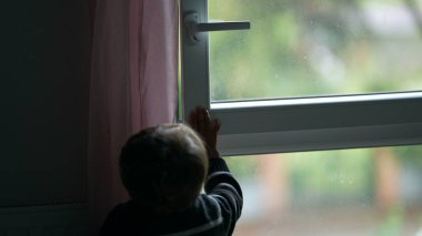 Child closing window. Toddler closes window