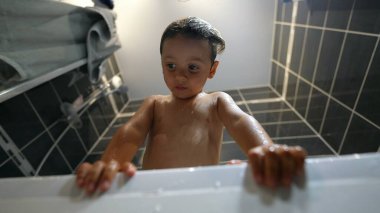 Wet Child inside bathub during washing routine. Bathing little boy