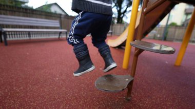 Little boy stepping down from playground structure steps equipment