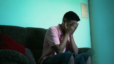 A frustrated young hispanic man covers face with hands feeling anxious. Preoccupied person