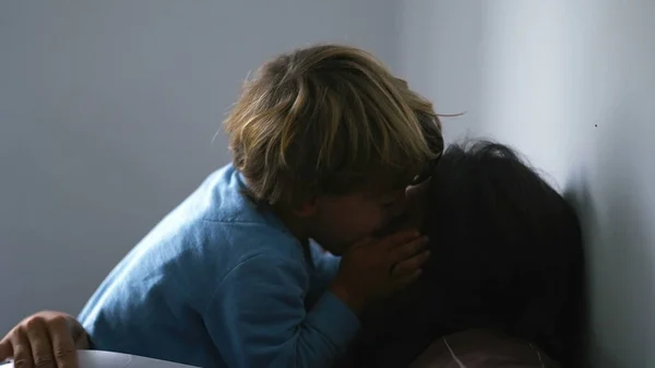 Little boy biting mother nose, real life authentic family moment at home