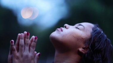 Young woman praying in the rain feeling the presence of God