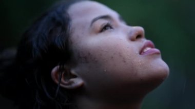 Gülümseyen mutlu Güney Amerikalı kadın yağmur altında ağır çekimde duruyor.