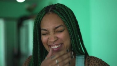 one young black woman laughing and smiling. Person burst laughing out loud