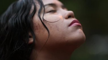 Yağmur altında gülümseyen genç kadın, yağmur yağarken dışarıda duran kişi.