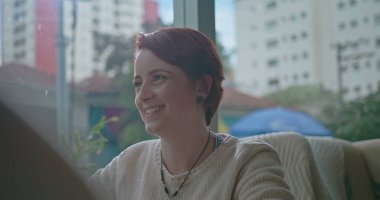 Genç bir kadın gülüyor ve arkadaşlarıyla takılıyor. Kızıl saçlı kızın yakın çekimi kahve dükkanındaki konuşmada güler.