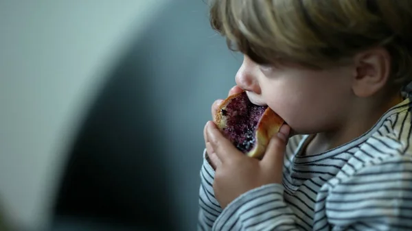 Child eating morning bread with jelly for breakfast