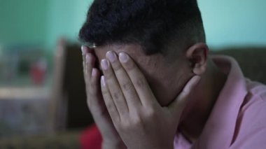 One anxious hispanic young man covering face with regret emotion
