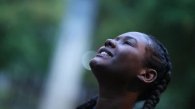 Genç siyah kız yağmur altında dışarıda duruyor. Gülümseyen mutlu siyah kadın