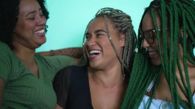 Young women hanging out together laughing and smiling. Three hispanic black latina female girlfriends spontaneous laugh
