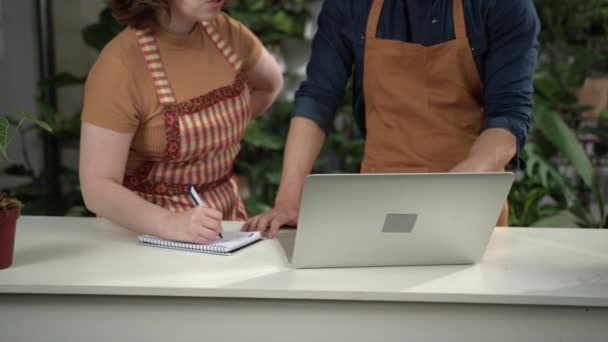 Male Female Staff Wearing Aprons Discussing Online Orders Front Laptop — Stock Video