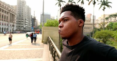 Pensive black man standing in urban downtown city