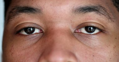 Close-up young black man eyes looking at camera, macro african person face