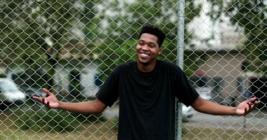 Black man shrugging. Confused African person showing doubt and smiling
