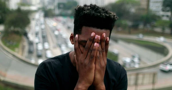 Anxious young black African man suffering in city