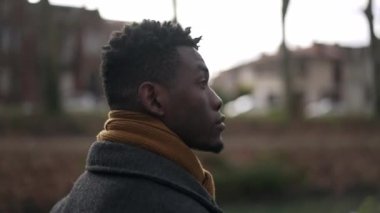 Elegant black man walking outside in nature park during winter season 