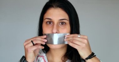 Censored young woman putting mouth tape unable to speak up. Silenced girl victim
