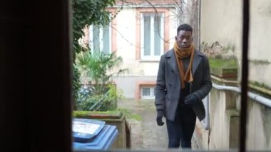 Hurried young black man leaving home opening front door