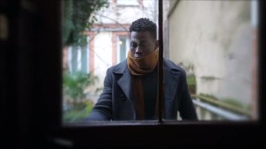 Young man opening front door walking through corridor stepping outside leaving home