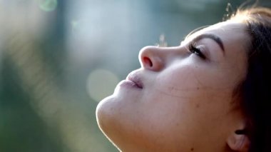 Young woman opening eyes with faith and hope to the sky