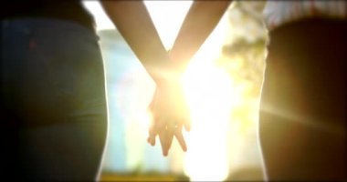 Joining hands together in sunlight flare. Close-up of two people uniting for a cause in 4K