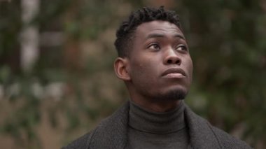 Pensive young black man standing in thought