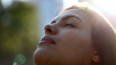 Young woman face opening eyes in meditation and contemplation looking up at the sky with hope and faith