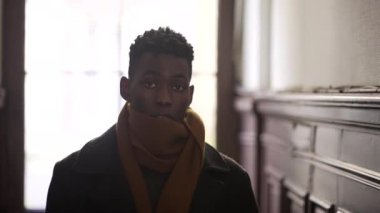 Young black man wearing scarf winter clothing walking in corridor leaving home