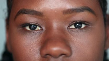 Young black woman looking at camera, close-up macro African face