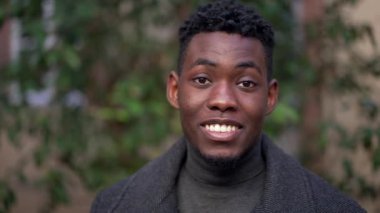 Friendly black African man smiling at camera standing outside