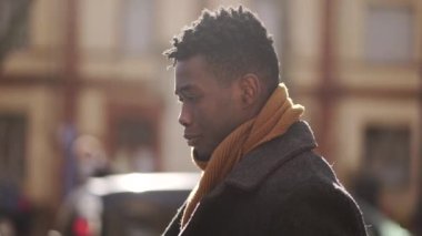 Pensive black man walking outside in city thinking by himself during winter season, tracking shot