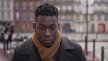 Pensive young black man walking outside in city in the cold