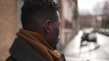 Concerned black man standing outside in city, close-up face portrait thoughtful expression