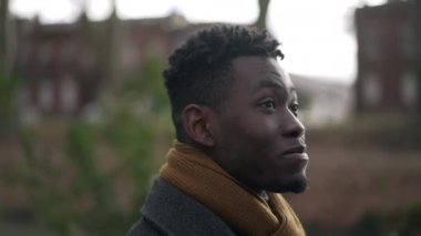 Pensive Young black man walking outside in park nature during winter season