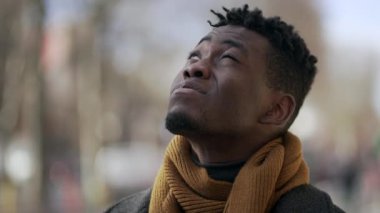 Siyah adam binaları gözetlerken gözlerini kısıyor.