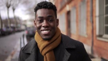 Charismatic happy black African man walking in city downtown smiling at camera during winter season