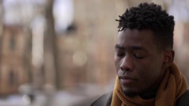 Pensive black African male walking outside in city while daydreaming alone