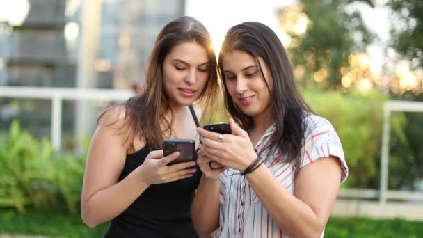 Дві Молоді Тисячолітні Жінки Стоять Вулиці Перевіряють Смартфони Разом Дівчата — стокове відео
