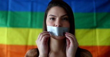 Woman removing tape from mouth, LGBT pride freedom concept