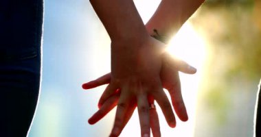 Close-up two hands held together with sunlight lens-flare in background